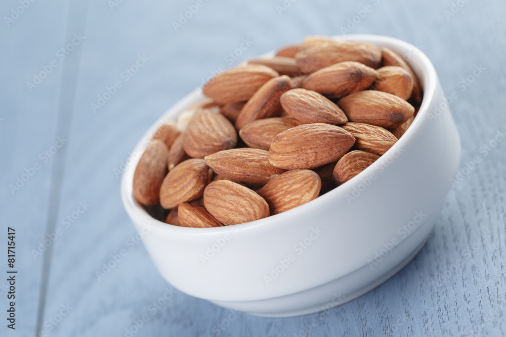 roasted almonds in white bowl on wooden table roasted almonds in white bowl on wooden table