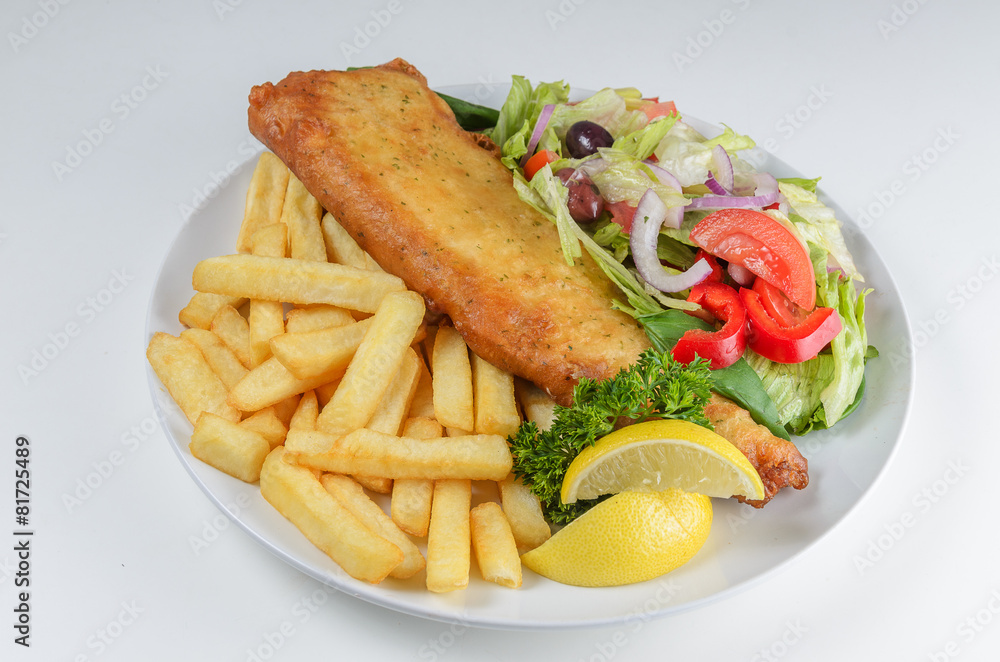 FIsh and chips serrved with salad on white plate