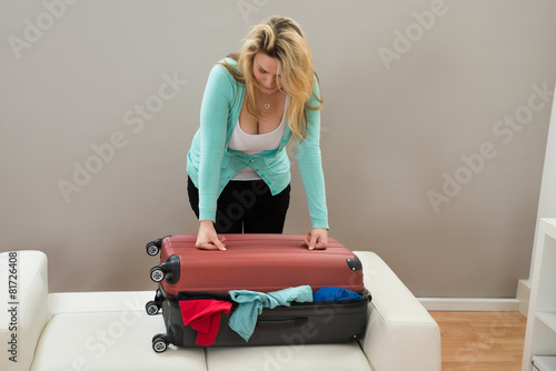 Woman Trying To Close The Suitcase