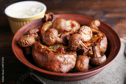 Baked potatoes with mushrooms in bowl and sauce