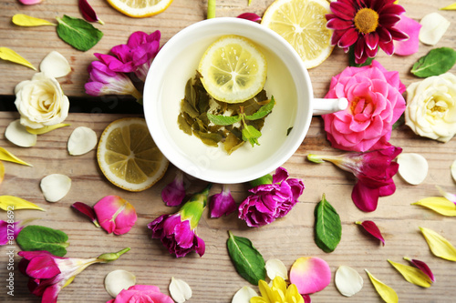 Cup of herbal tea with beautiful flowers, on wooden background