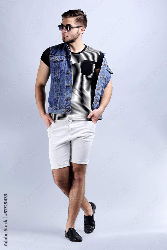 Man in white shorts and jeans vest on gray background Man in white shorts and jeans vest on gray background