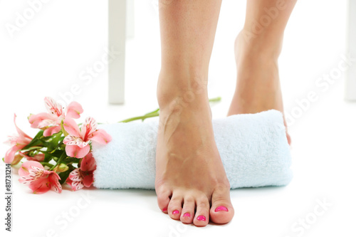 Beautiful female legs, towel and fresh flowers isolated on white background