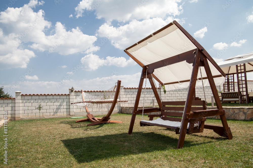 Swinging bench and hammock in the garden. Cloudy sky Swinging bench and hammock in the garden. Cloudy sky