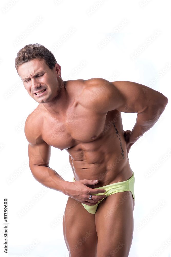 Muscular handsome man holding his back in pain