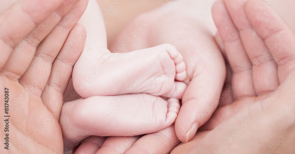 Mother and father hands holding feets of newborn baby, closeup Mother and father hands holding feets of newborn baby, closeup