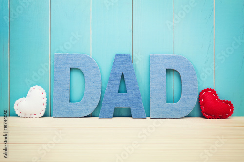 DAD text letters with hearts over blue wooden background