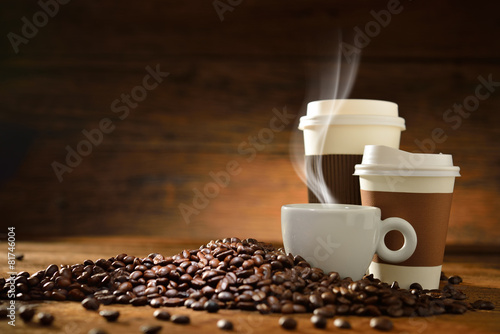Cups of coffee and coffee beans on old wooden background