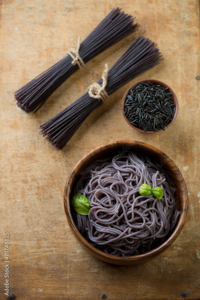 Noodles made of black rice, rustic wooden surface, above view Noodles made of black rice, rustic wooden surface, above view