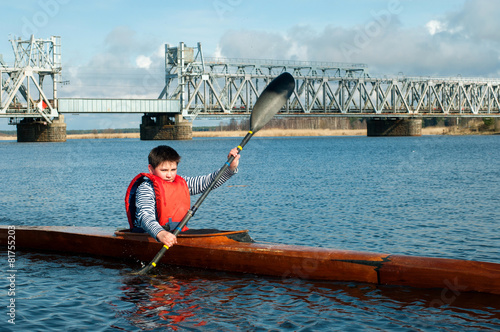 The boy rowing in a kayak on the river