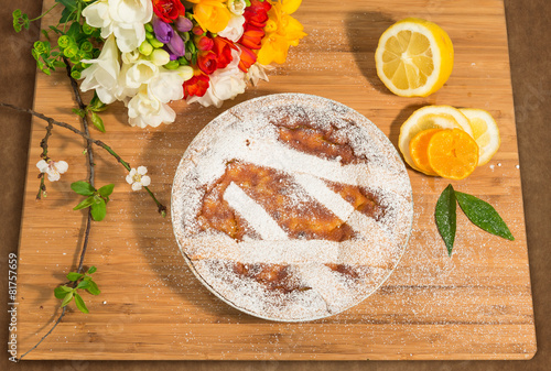 Pastiera napoletana con fiori ed agrumi su piano di legno photo