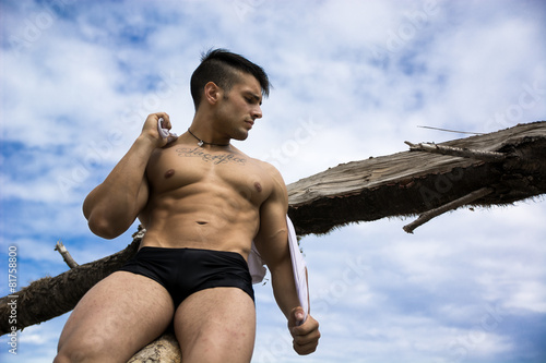 Attractive muscular shirtless young man in nature