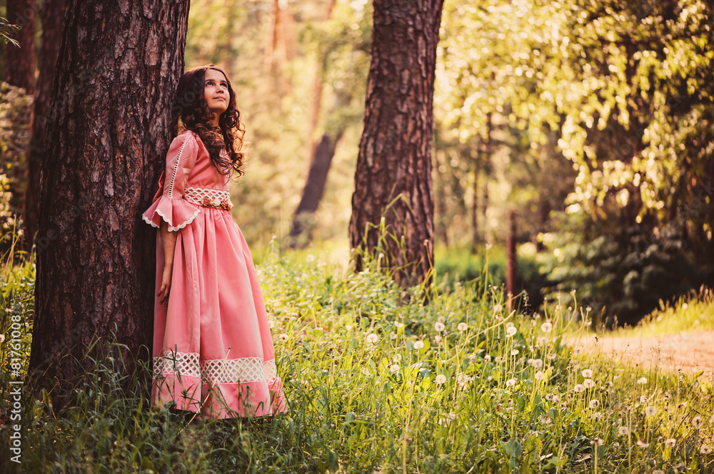 smiling child girl in pink princess dress in summer forest