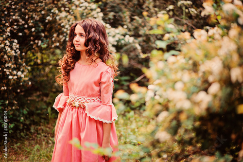 smiling child girl in pink princess dress in summer forest