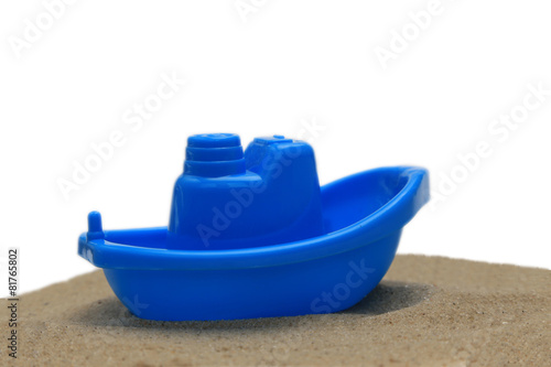 Plastic toy boat on sand isolated on white