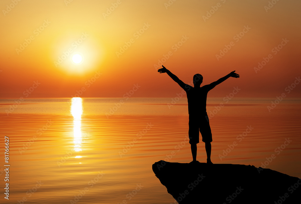 Silhouette of a man on a mountain top on sunset background