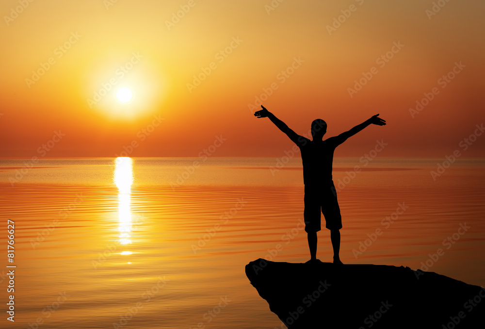 Fototapeta premium Silhouette of a man on a mountain top on sunset background