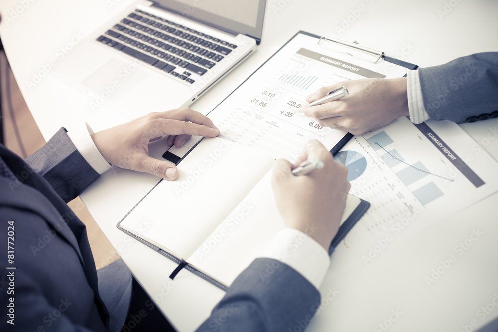 Two businessmen looking at report and having a discussion in off Two businessmen looking at report and having a discussion in off