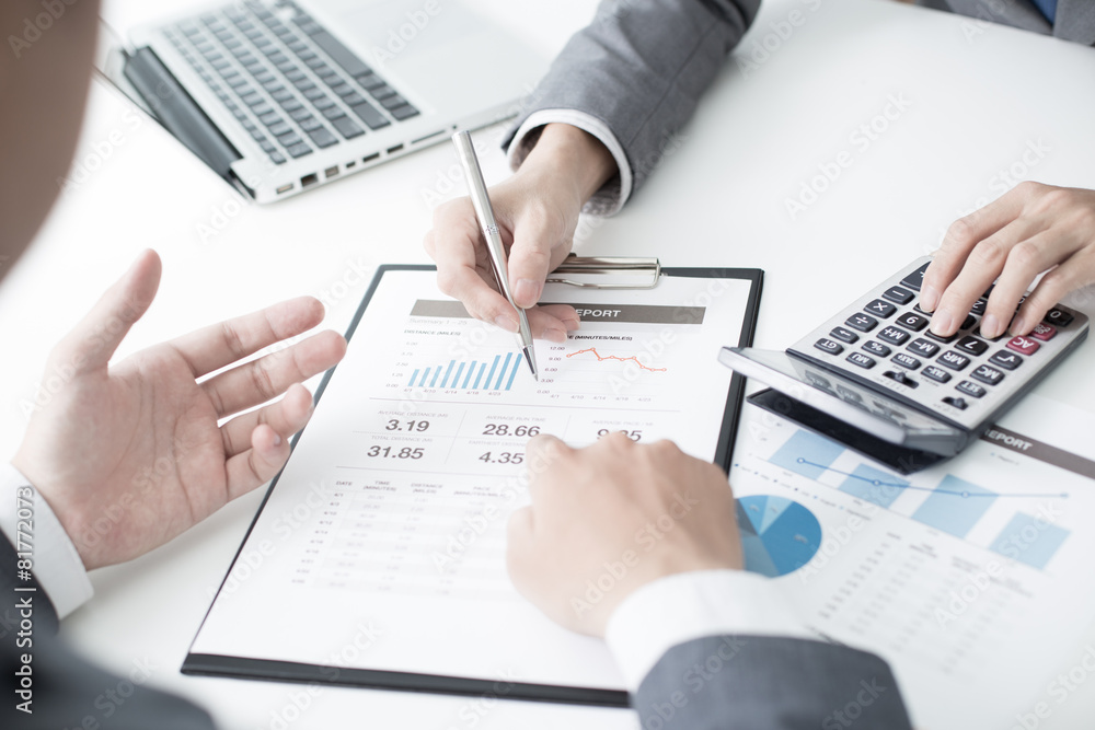 Two businessmen looking at report and having a discussion in off Two businessmen looking at report and having a discussion in off