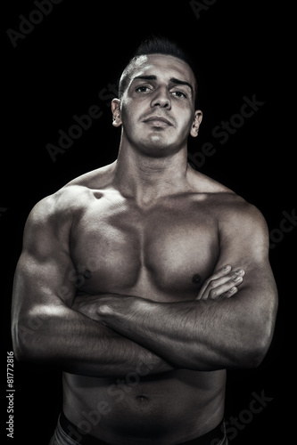 Low light portrait of bodybuilder over black background