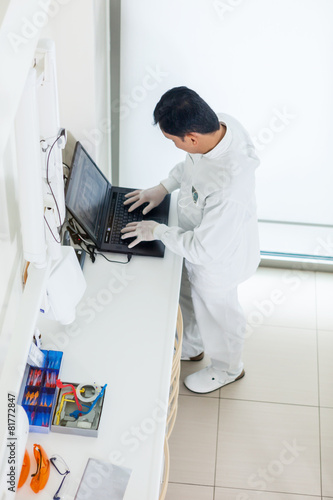 top view of asian dentist working on a computer and checking his