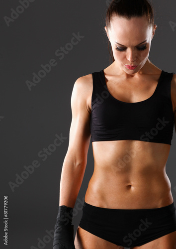Muscular young woman  standing on gray background