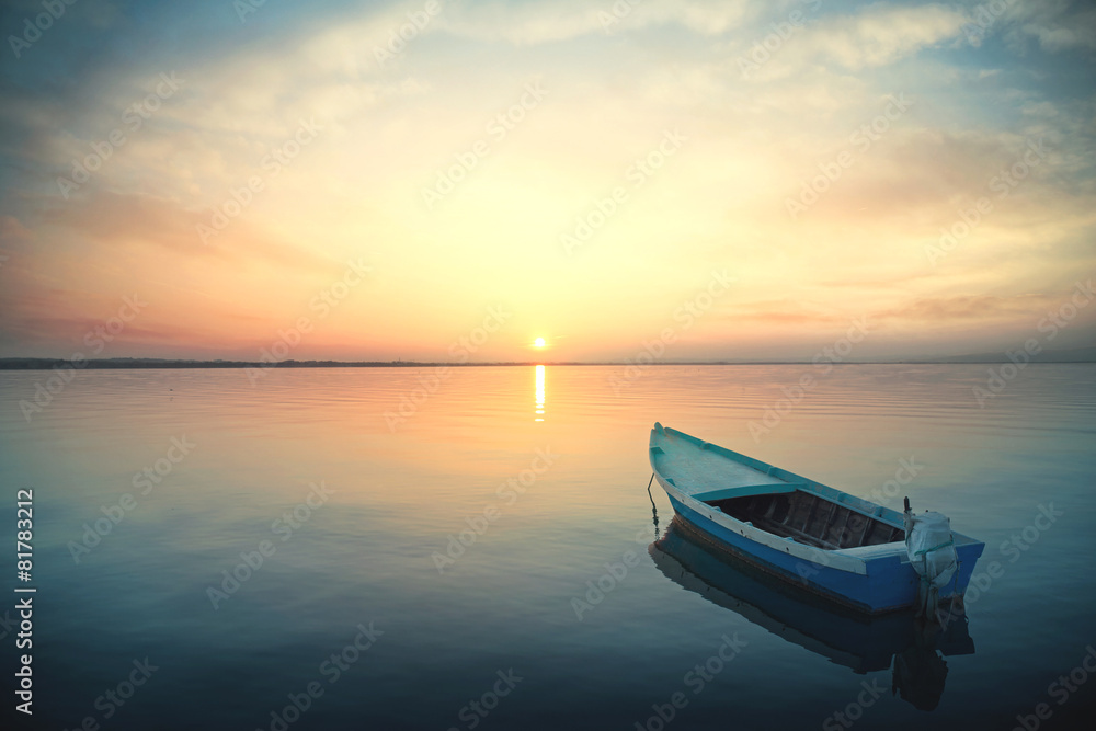 Fototapeta premium Canoe floating on the calm water under amazing sunset