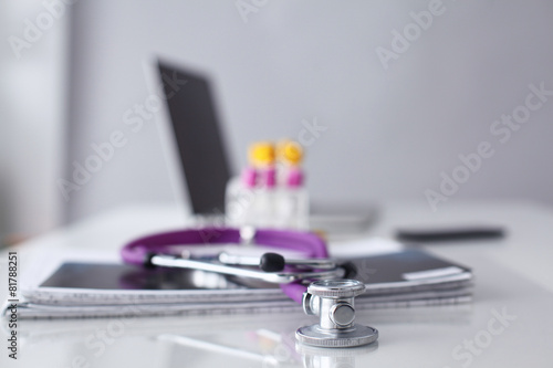 Violet stethoscope near laptop computer