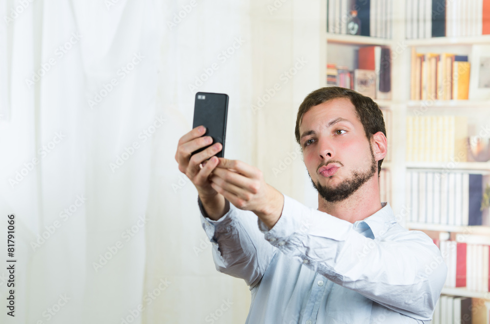 attractive young man using cell phone to take a selfie attractive young man using cell phone to take a selfie