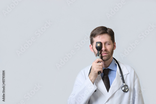 Physician looking through ophthalmoscope photo