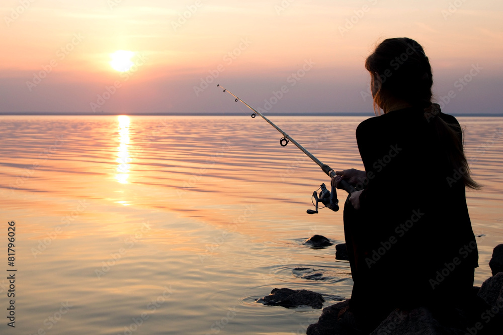 young girl fishing at sunset near the sea Photos