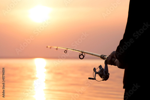 young girl fishing at sunset near the sea