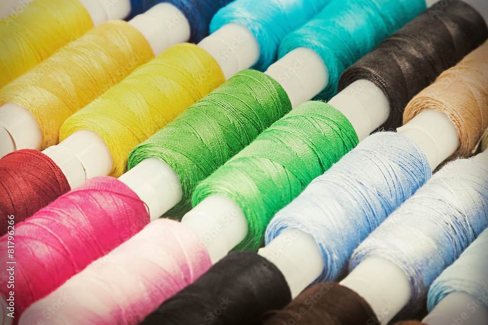 Multicolor sewing threads on wooden background Multicolor sewing threads on wooden background