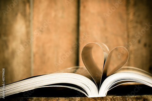 Heart from book pages on wood background