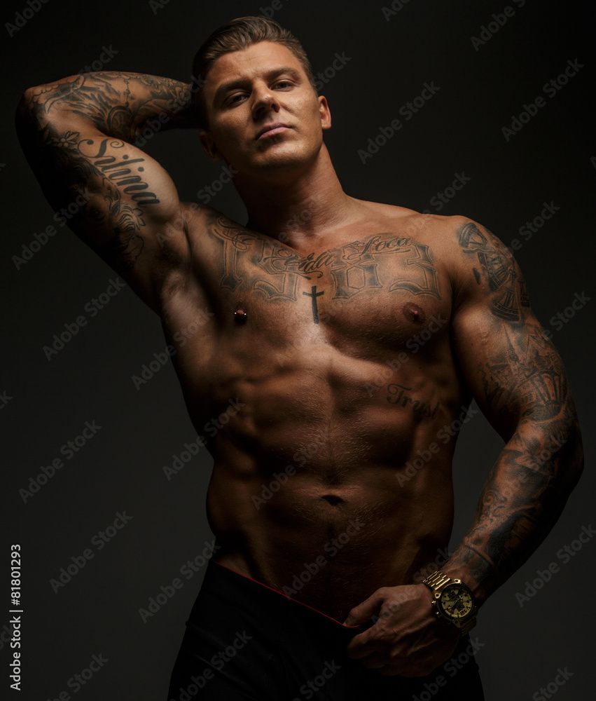 Fototapeta premium Tattooed muscular guy posing on gray background