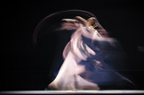 Blurry dancers in dynamic dance. Dancers dance on the dark stage. Slow shutter speed photography. .