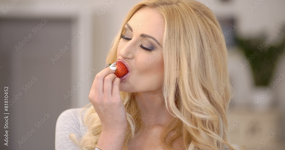 Healthy attractive blond woman eating a strawberry Healthy attractive blond woman eating a strawberry