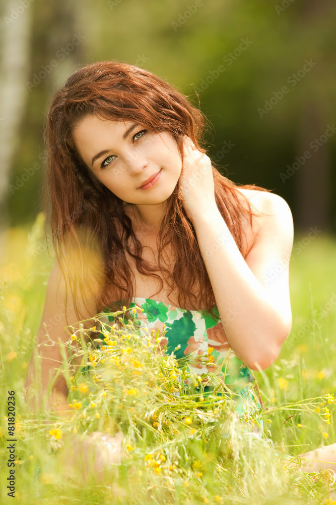 Young redhead woman in the park with flowers Young redhead woman in the park with flowers