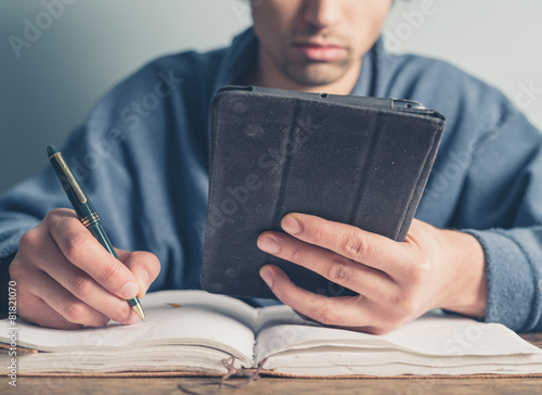 Man in bathrobe using table and taking notes photo