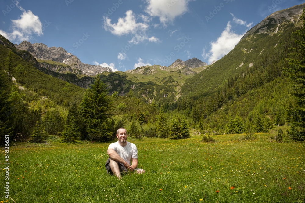 Naklejka premium Man relaxing in a forest clearing in the alps
