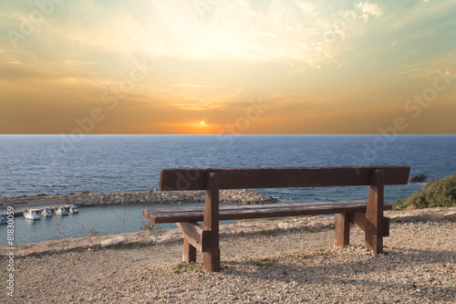 Wooden bench on the beach against the setting sun