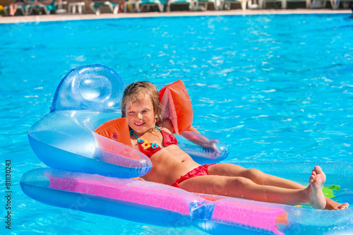 Child swimming on inflatable beach mattress.