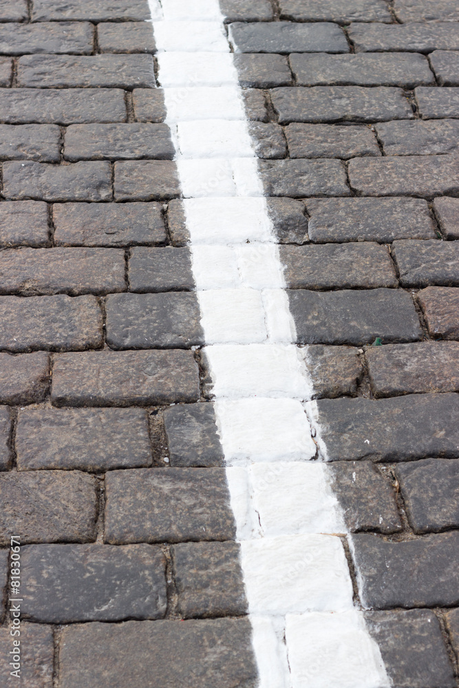 The white line on the road receding the stone