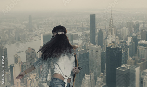 Trendy girl with skateboard in her hands on NY City background