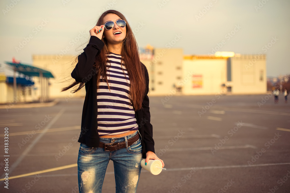 Fototapeta premium Outdoor fashion closeup portrait of nice pretty young hipster woman posing in sunglasses at sunset walks along the streets of the city.