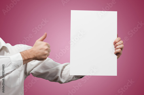 Hands holding a white paper blank isolated on pink background