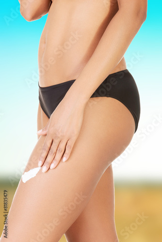 Woman applying cream on her leg.