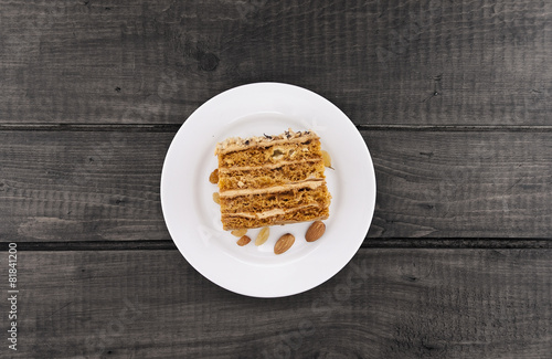 Cake slice with nut on plate on wooden table, top view.