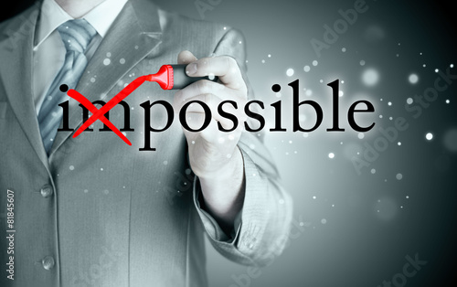 Businessman Hand turning the word Impossible into Possible with