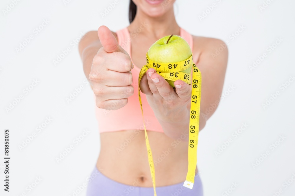 Slim woman holding apple with measuring tape Slim woman holding apple with measuring tape